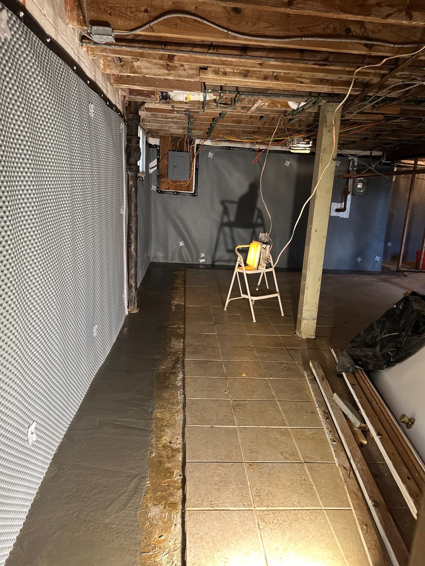 Interior basement waterproofing installation with drainage channel and waterproofing panels being sealed in concrete